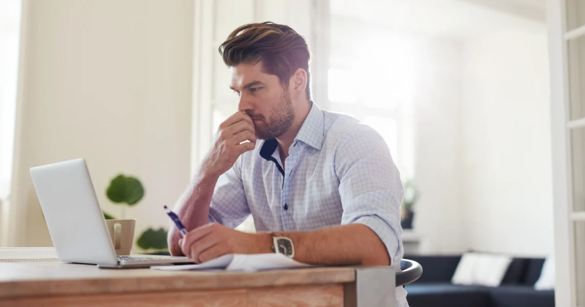 male working from home, looking at laptop screen, thinking (1)