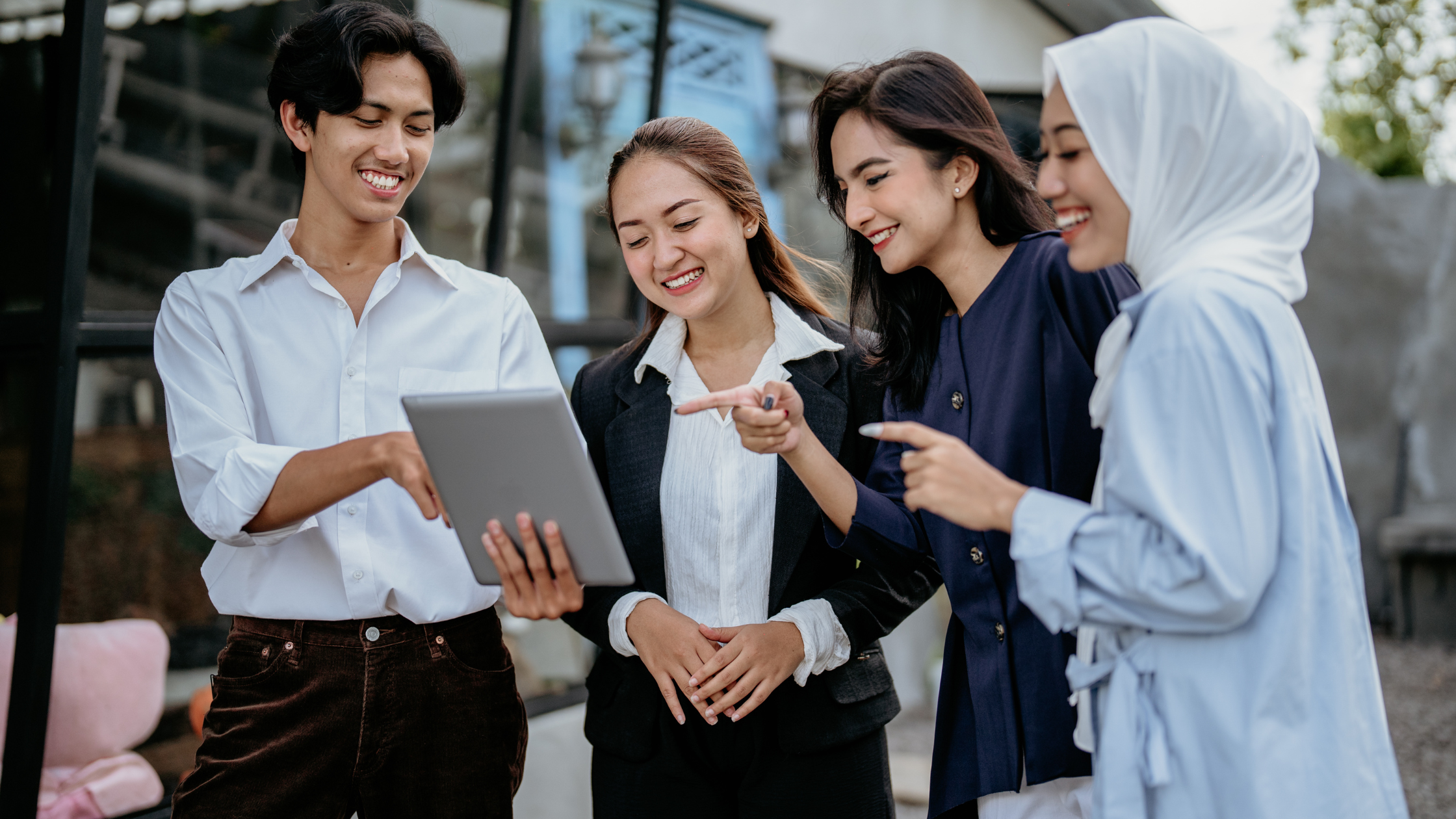 Photo of 4 colleagues standing around a tablet, looking at something on the screen