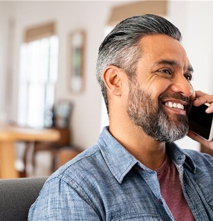 Featured photo of male sitting on couch talking on cell phone smiling