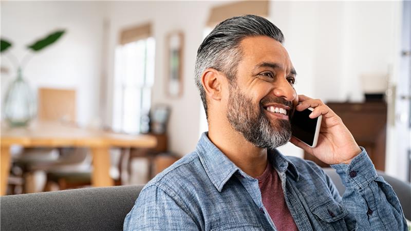 Featured photo of male sitting on couch talking on cell phone smiling