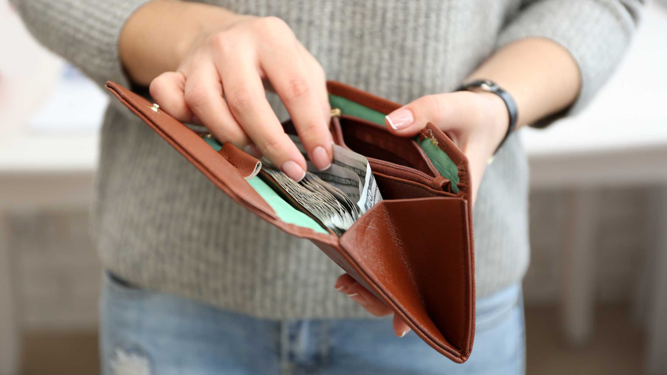 Featured photo of person holding an open wallet full of cash
