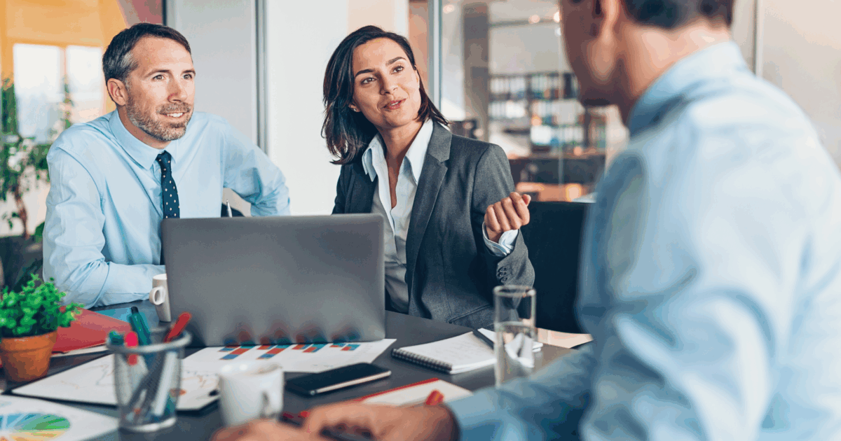 Three coworkers gathered at table in discussion