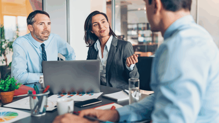 Three coworkers gathered at table in discussion
