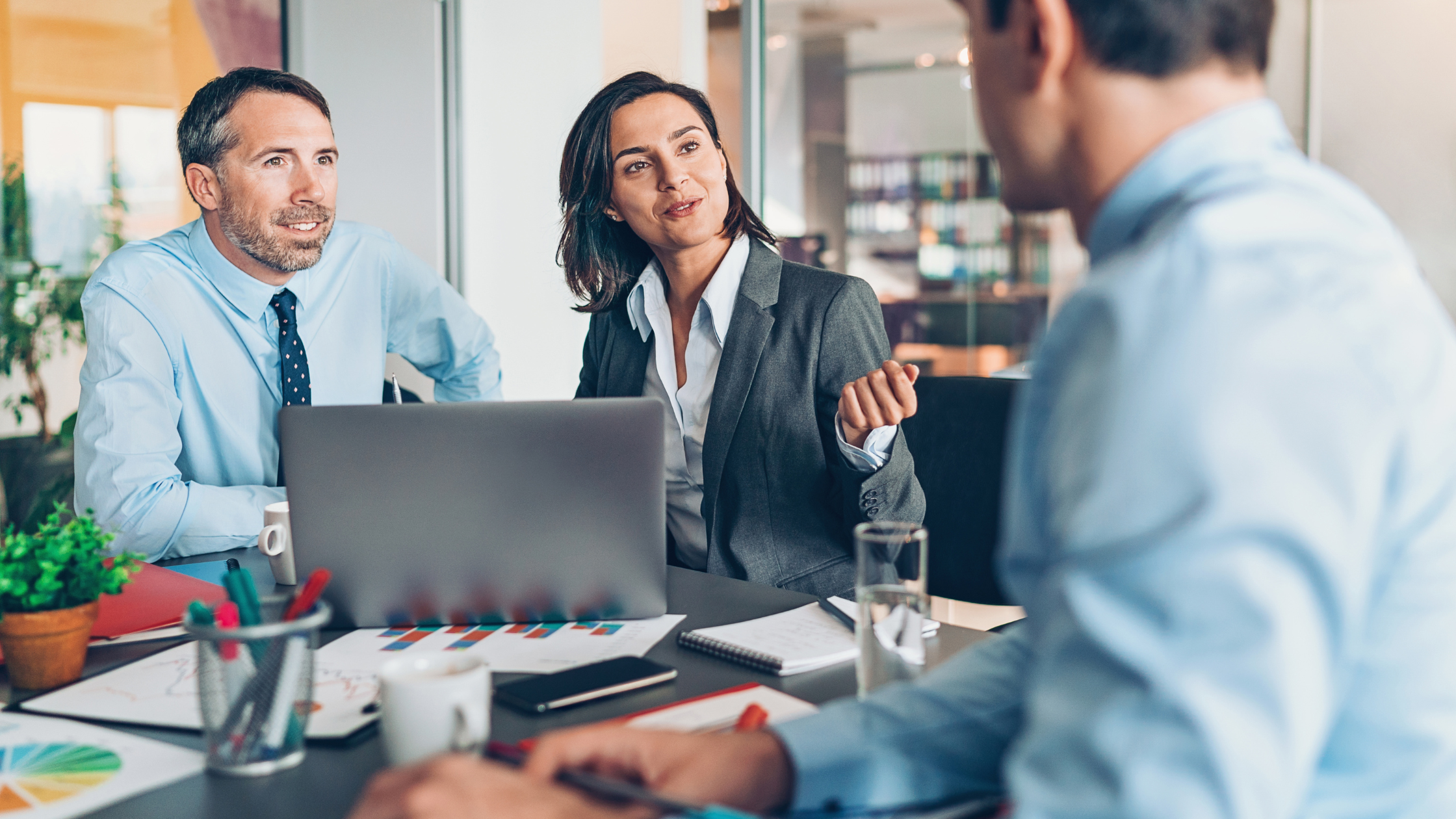 Three coworkers gathered at table in discussion