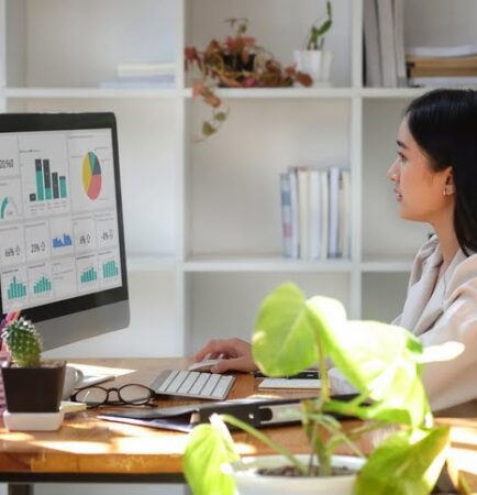 Professional female analyst reviewing performance dashboards on a computer, symbolizing the benefits of outsourcing for businesses to gain specialized expertise and data-driven insights.