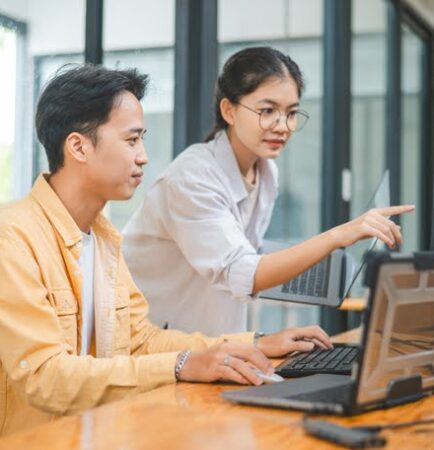 Two young customer service professionals collaborating, symbolizing digital customer service trends like immediate tech support and omnichannel experience.