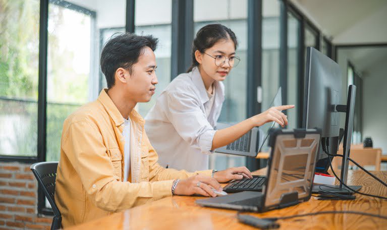 Two young customer service professionals collaborating, symbolizing digital customer service trends like immediate tech support and omnichannel experience.