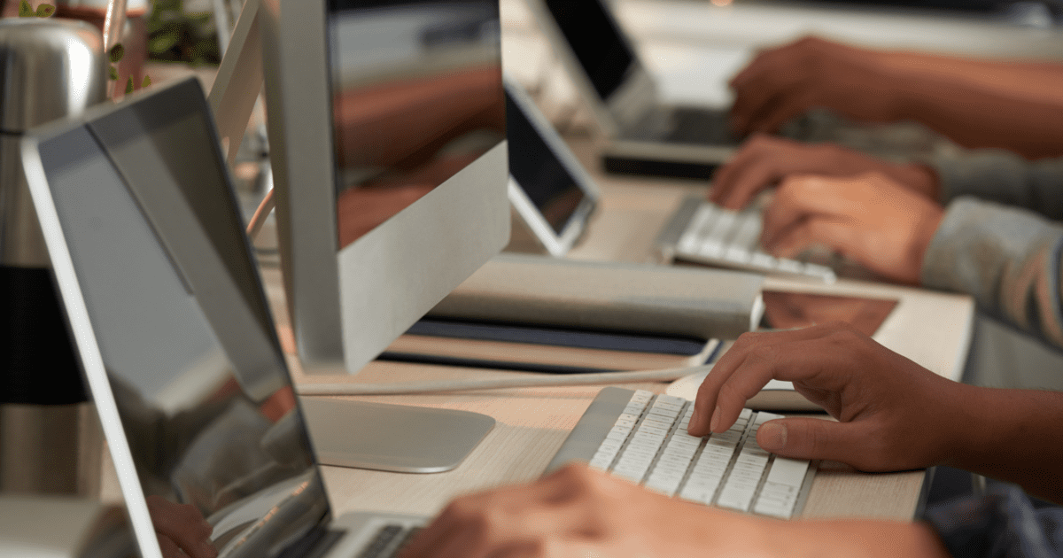 Professionals working at computer workstations in a modern office, illustrating how everyday employee actions, secure workflows, and technology come together to support human-centered cyber resiliency and protect digital operations.