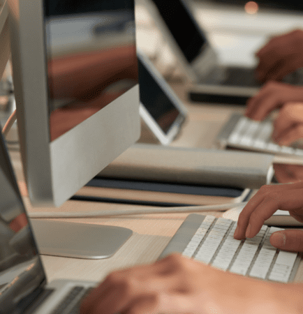 Professionals working at computer workstations in a modern office, illustrating how everyday employee actions, secure workflows, and technology come together to support human-centered cyber resiliency and protect digital operations.