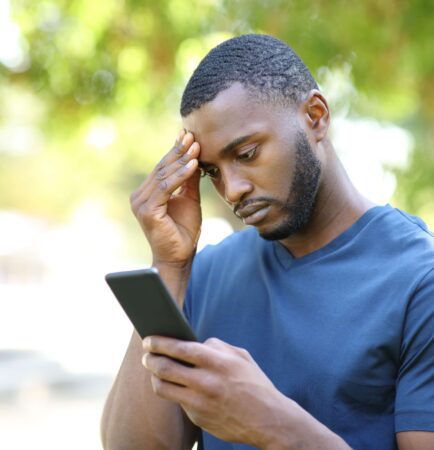 Man looking concerned while checking a billing notification on her phone