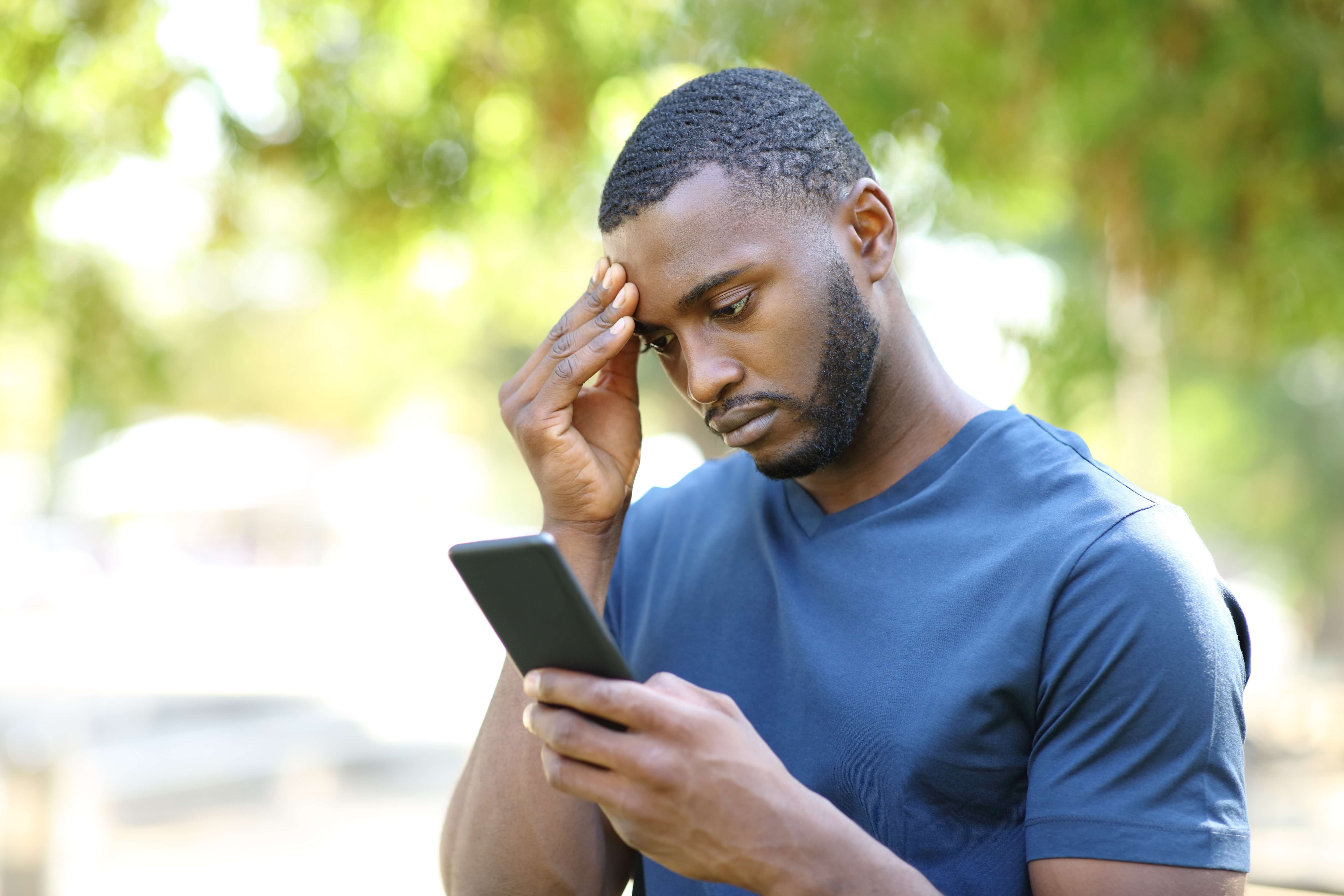 Man looking concerned while checking a billing notification on her phone