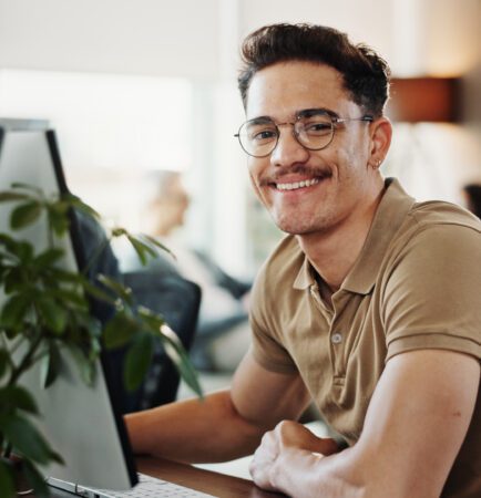 Computer, portrait and web development with smile of man in creative workplace for coding or design. Cybersecurity, happy and system infrastructure with employee person in office as website developer.
