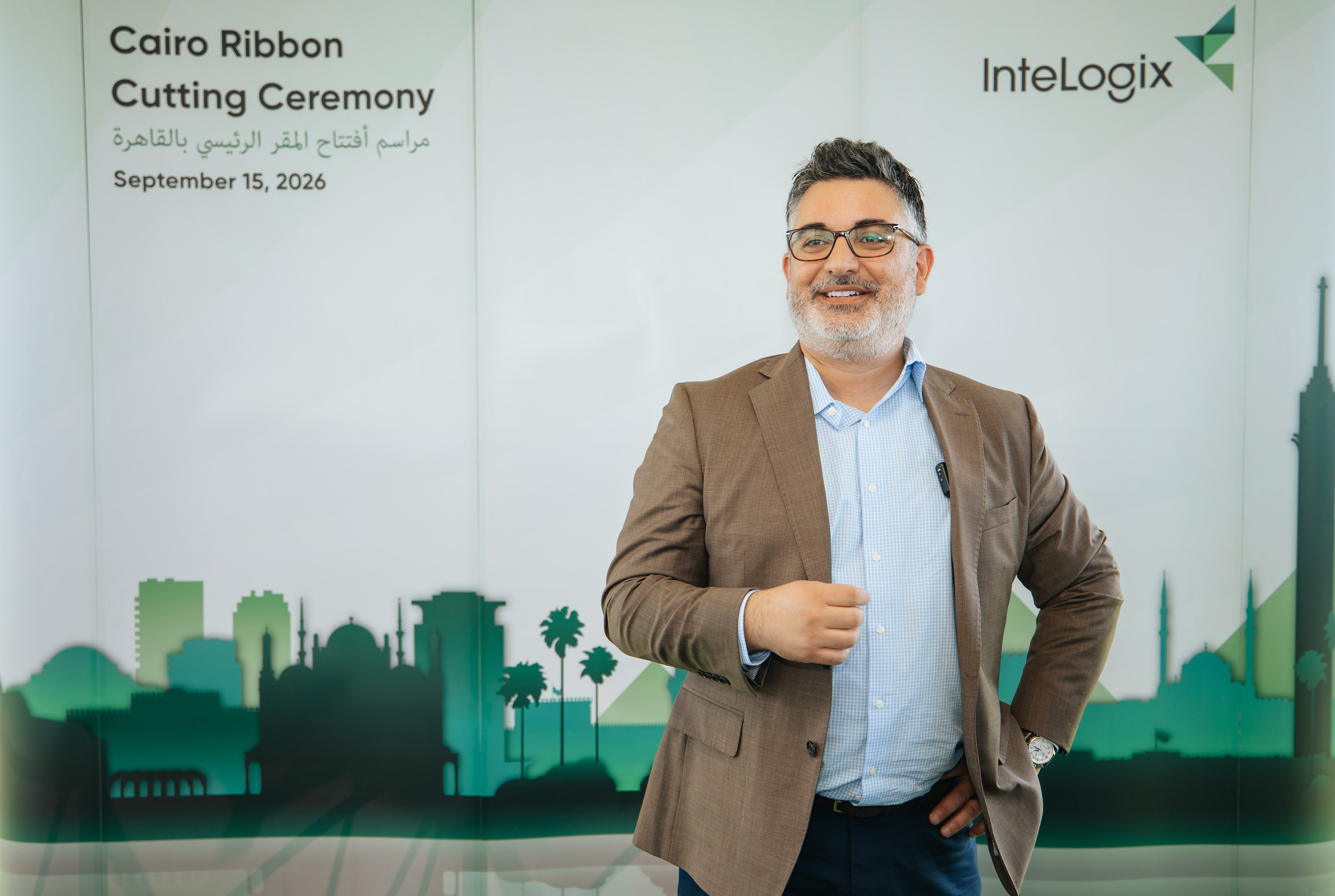Mario Baddour, InteLogix CEO and President, smiling in front of the Cairo Ribbon Cutting Ceremony backdrop featuring a green Cairo skyline