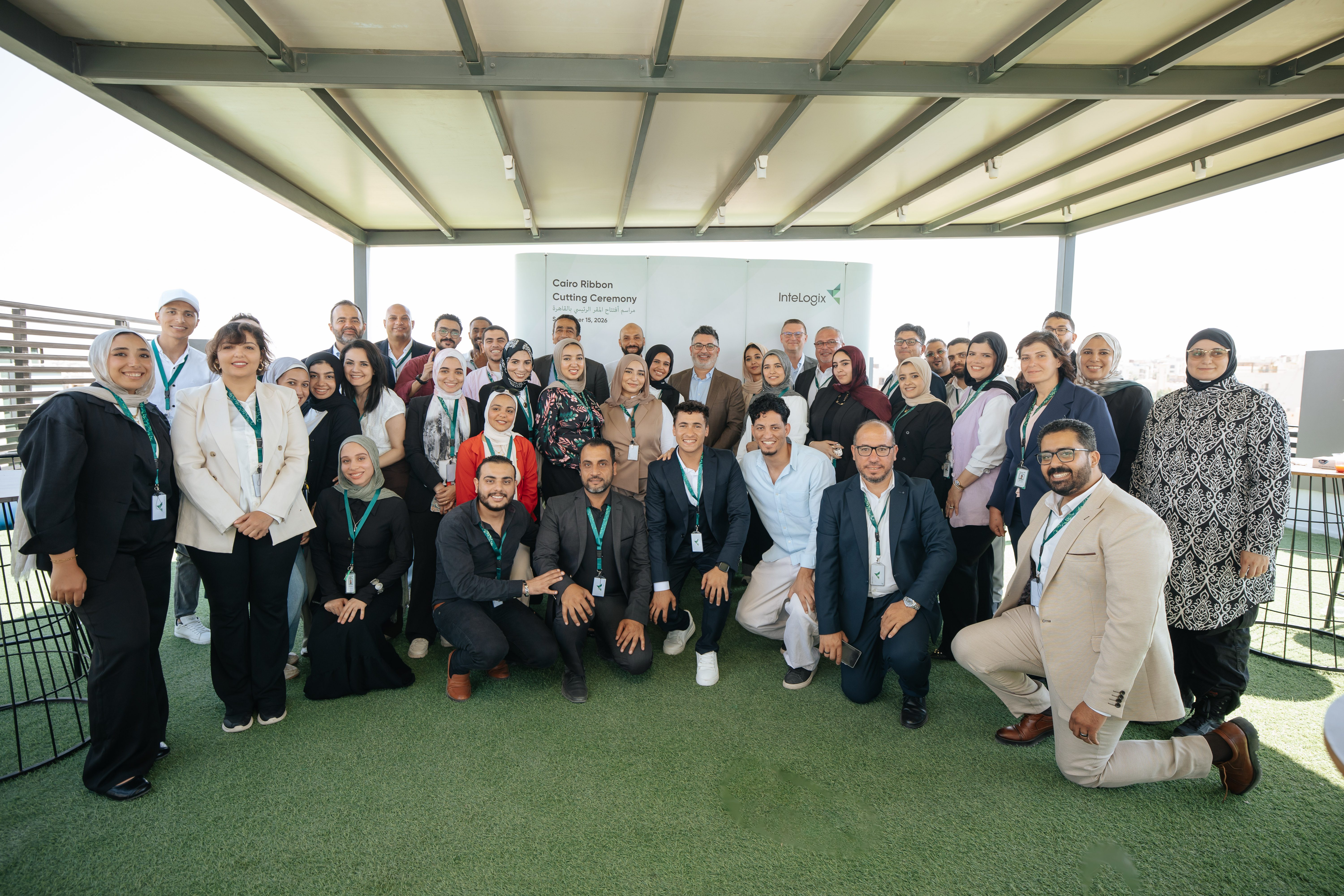 The InteLogix Egypt team gathered on the rooftop terrace of the new New Cairo facility in front of the Cairo Ribbon Cutting Ceremony backdrop